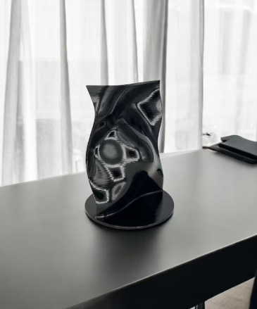 Black 3D printed abstract sculptural vase with high-gloss finish displayed in a modern minimalist interior.